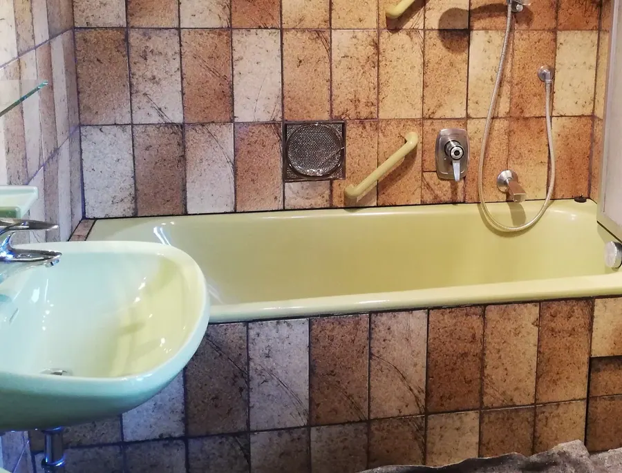 Vorher: Altes Bad mit Badewanne und braunen Fliesen
